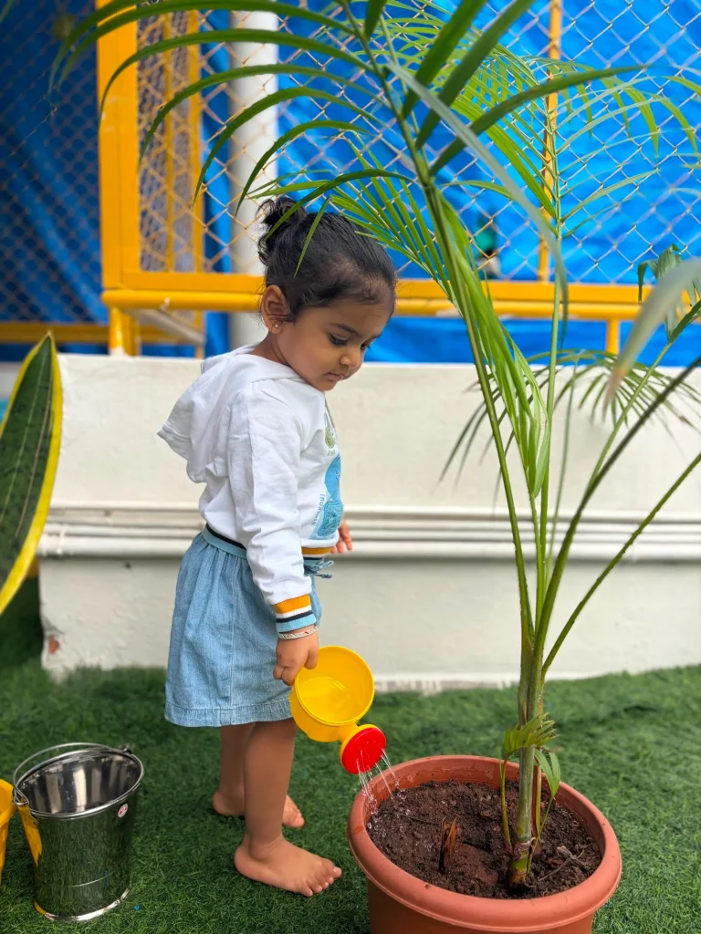 Toddler watering a plant at ACE Montessori, Jayanagar, Bangalore